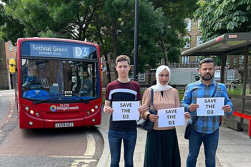 Lib Dem activists Dominic Buxton, Rabina Khan and Mahbub Alam hold signs reading Save the D3 bus in front of the D3 bus on Wapping Lane